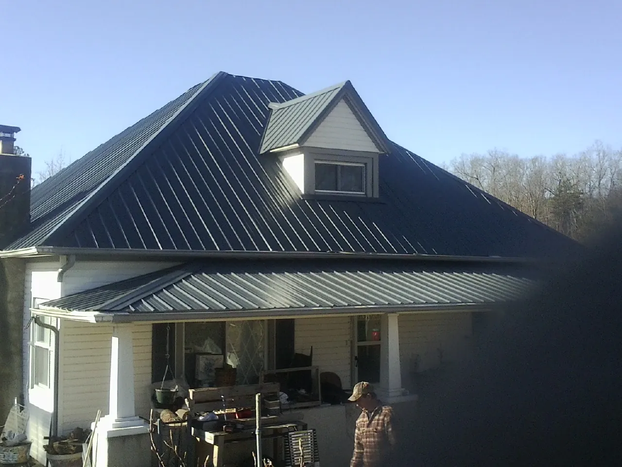 Dark blue standing seam metal roof with a dormer above a front porch in Durham