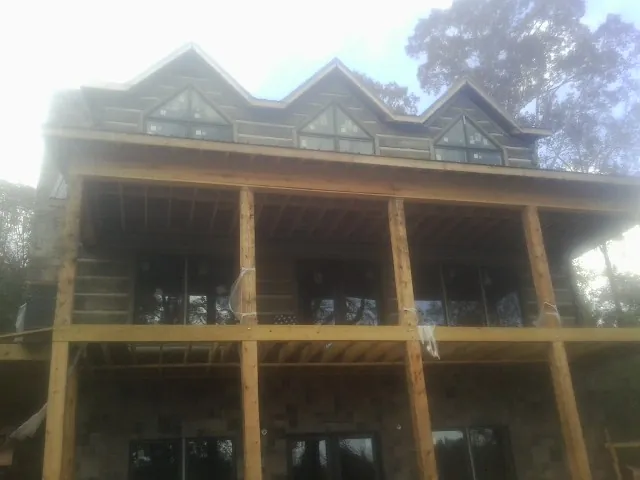Dormers and porch framing on a large log home under construction — Roof Coating work by our crew in Durham